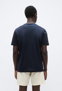 Μπλε ναυτικό κοντομάνικο μπλουζάκι από βαμβάκι, με λαιμόκοψη crew και χαλαρή εφαρμογή, με ορατή ραφή στο πίσω μέρος.