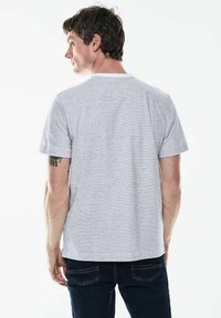 Šedé a bílé pruhované tričko s kulatým výstřihem, krátkými rukávy a volným střihem, spárované s tmavě modrými džíny.