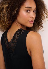Black tank top featuring a lace detail at the back neckline. Smooth texture with a fitted shape and sleeveless design.