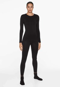 Schwarzes, langärmliges Thermoshirt und Leggings aus elastischem Material, mit Rundhalsausschnitt und tailliertem Schnitt. Gesamte glatte Textur.