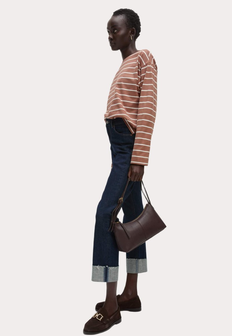 Bruin en wit gestreepte lange mouwen top gecombineerd met hoge taille donker denim jeans en bruine loafers. Schoudertas heeft een gladde textuur.