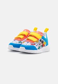 Zapatillas Adidas para niños con tiras amarillas, punteras azules, lengüetas coral y diseños de Mickey Mouse en los lados blancos.