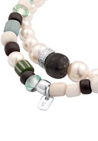 Halsband med pärlor och glaspärlor som har oregelbundna former i vitt, grönt och svart, med en silverlåsning och ett märke som är stämplat "925."