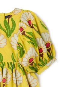 Vestido amarillo con grandes flores blancas y centros rosas, y hojas verdes. Mangas abullonadas con detalles fruncidos en los puños y en la cintura.