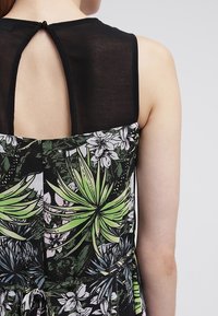 Mnohobarevné šaty s botanickým potiskem zelených rostlin a květin. Černý, průhledný zadní díl s klíčovou dírkou na výstřihu.