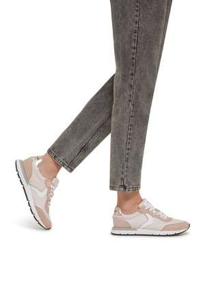 Light pink and beige athletic sneakers with white accents, featuring a mixed material design and a textured sole, paired with gray jeans.