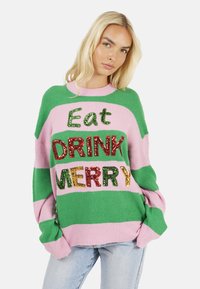 Maglione multicolore con righe verdi e rosa che presenta il testo con paillettes "Eat DRINK MERRY." Taglio ampio con maniche larghe e texture morbida.