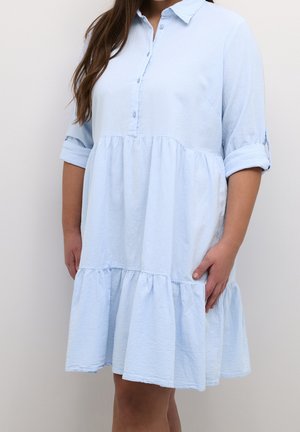Lyseblå skjortekjole med krave, opkrogede ærmer og en flæsekant i lag. Fremstillet af tekstureret stof og har en afslappet pasform.