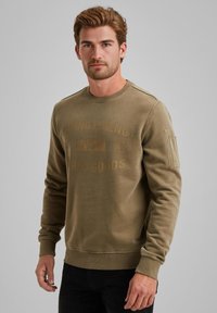 Olijfgroene sweatshirt met geribbelde ronde hals, textuurstof en gedrukt logo aan de voorkant. Heeft zijaansluitingen op de schouders en manchet sleeves.