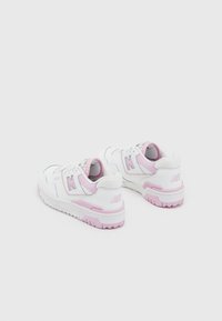 Zapatillas blancas y rosas con un upper texturizado, puntera redonda y suela de goma duradera. Presenta el logo 'N' y un collarín acolchado.