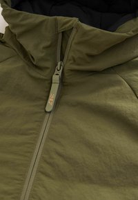 Olivgrüne Kapuzenjacke mit strukturierter Oberfläche. Verfügt über einen Reißverschluss vorne mit einem markierten Ziehband und einem glatten Innenfutter.