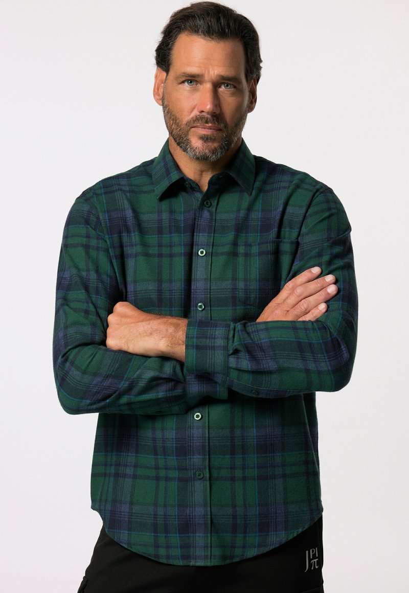 Camisa de franela a cuadros verdes y azul marino con cuello abotonado, mangas largas y un bolsillo en el pecho izquierdo. Textura suave, corte relajado.