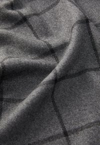 Tessuto grigio con un sottile motivo a quadretti di un grigio più scuro. Texture morbida con una leggera lucentezza, drappeggiato delicatamente per rivelare profondità e strati.