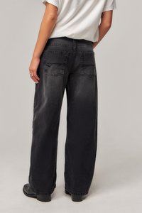 Svart vid bukse laget av denim med en falmet tekstur, baklommer og en avslappet passform, kombinert med svarte hælboots.