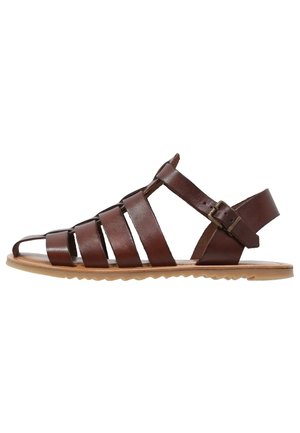 Brown leather sandals with a strappy design, open toe, and adjustable ankle buckle. The sole is flat and textured for grip.