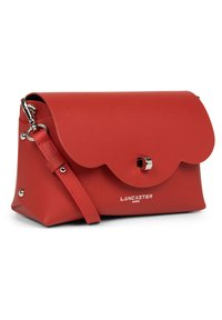 Borsa in pelle rossa con patta ondulata, hardware in argento, tracolla regolabile e marchio impresso sul davanti. Texture liscia.