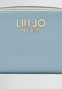 Svijetloplava kožna novčanik s zlatnim logotipom "LIU·JO MILANO", zatvaranje na zip, glatka tekstura i kontrastne detalje šavova.