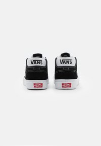 Zwarte suede high-top sneakers met witte accenten, voorzien van een witte rubberen zool en een gelabelde hiel-lap. Opvallende stiksels aan de zijkanten.