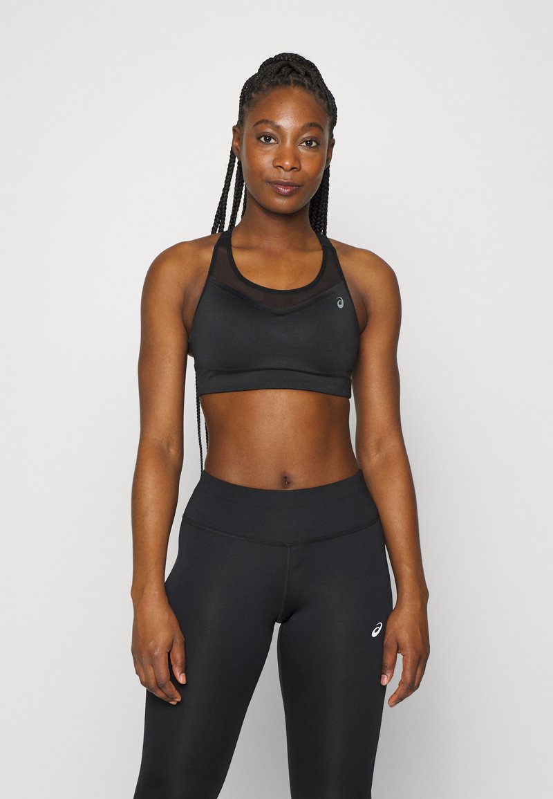 Soutien-gorge de sport noir avec un haut en filet et des bretelles larges, associé à un legging noir taille haute avec des détails de couture subtils.