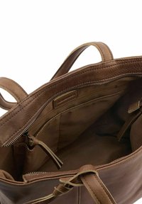 Interieur van een bruine leren tote bag met rits- en steekzakken; zachte textuur en gevoerd met een lichter stof voor contrast.