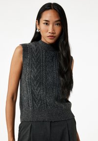 Pull en maille gris foncé sans manches avec col montant, présentant un motif en chevrons texturé et un ourlet côtelé. Fini lisse et silhouette ajustée.