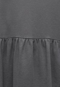 Close-up of dark gray fabric with a gathered seam creating soft folds and texture on the lower portion.