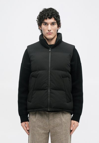 Gilet imbottito nero con colletto alto, chiusura con zip e due tasche frontali. Presenta maniche in maglia nera a coste e una finitura liscia e opaca.