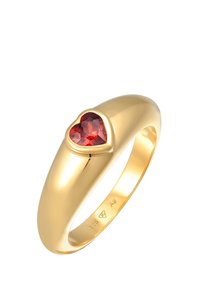 Culoare aurie cu un finisaj lustruit, având la mijloc o piatră prețioasă roșie în formă de inimă. Gravată cu "925" pe interiorul inelului.