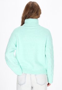 Mintgrüner Strickpullover mit hohem Kragen, ausgestattet mit Kabelstrickärmeln und geripptem Saum, entworfen für eine lässige Passform.