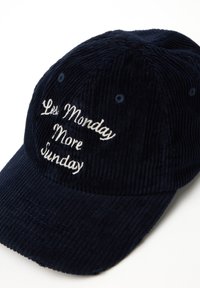 Gorra de béisbol de pana color marino con el texto bordado "Menos Lunes Más Domingo" en blanco. Presenta un ala curvada y detalles cosidos.
