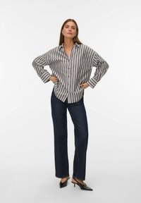 Camicia a righe grigia e bianca, con vestibilità rilassata, maniche lunghe e orlo curvo, abbinata a jeans dritti blu scuro.