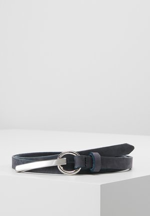 Cinturón de cuero azul marino con una hebilla redonda plateada y una punta de metal plateada, enrollado sobre una superficie blanca contra un fondo gris claro.