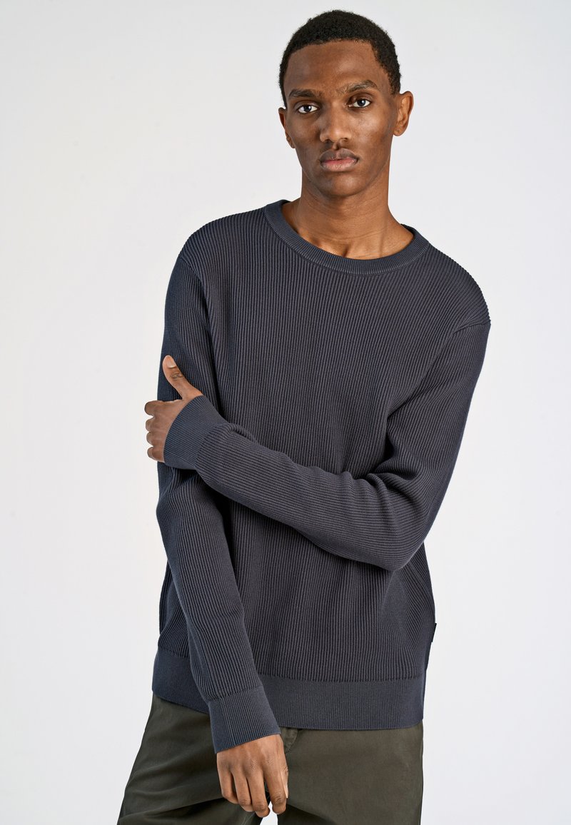 Maglione a coste navy con colletto rotondo e maniche lunghe; presenta polsini allungati e una vestibilità comoda. Texture liscia.