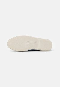 Schoenzool van textuurachtig crème rubber, met een vlak profiel en een lichte kromming bij de hiel. Beschikt over een gegraveerd logo detail.