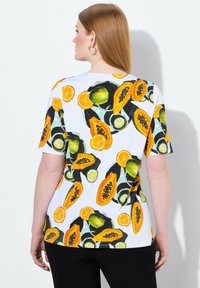 Camiseta blanca de manga corta con un vibrante estampado de frutas que incluye papayas, limas y naranjas. Fabricada con un tejido suave y ligero.