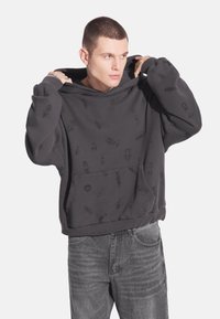 Ciemnoszara bluza z kapturem z przednią kieszenią i wzorem owadów oraz czaszek. Miękka w dotyku, o luźnym kroju i regulowanym kapturze.