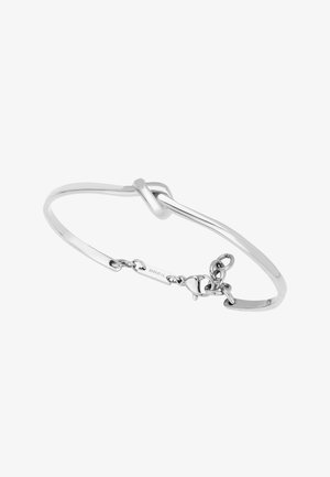 Srebrna bransoletka na nadgarstek z detalem w postaci węzła i małym zapięciem na łańcuszek, wygrawerowana z napisem "BREIL" na białym tle.