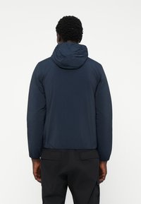 Navy lightweight jacket with a hood, featuring a smooth texture and elastic cuffs, viewed from the back.