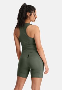 Groene sportieve tanktop en korte broek set. Beide gemaakt van een gladde, elastische stof. Beschikt over een racerback ontwerp en een getailleerde pasvorm.