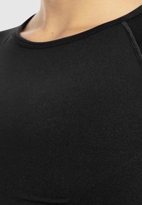 Schwarzes, enganliegendes Sportshirt mit Rundhalsausschnitt, nahtlosem Design und glatter Textur, das eine zweite Hautpassform für Komfort und Leistung betont.
