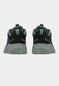 Selja musta ja sinise värvi Gore-Tex jooksujalanõusid, nähtaval tagant, hallide täpikestega vahe-detailsid ning türkiissinised tõmblukud ja sisekatted.