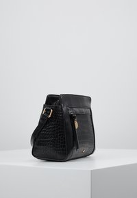 Schwarze Handtasche mit Krokodilprägung, goldenen Hardware-Elementen, rechteckiger Form und einer Seitentasche. Das Design verfügt über einen kurzen Schulterriemen.