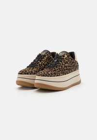 Des baskets plateformes à imprimé léopard présentent un dessus doux, des lacets noirs et une semelle intermédiaire beige contrastante avec une semelle extérieure en brun texturé.
