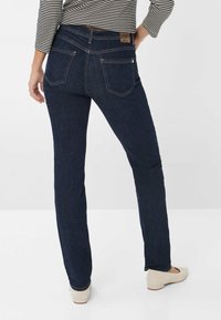 Jeans en denim bleu foncé avec une coupe droite, dotés d'une taille mi-haute, de poches arrière et de détails de couture subtils.