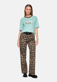 Mint green short-sleeve t-shirt with "LOVE" graphic; paired with brown leopard print wide-leg pants. Black belt and chunky black shoes.
