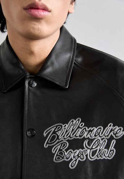 Čierna kožená bunda s zapínaním na cvoky a špicatým golierom. Na hrudi sa nachádza biele vyšívané logo "Billionaire Boys Club".