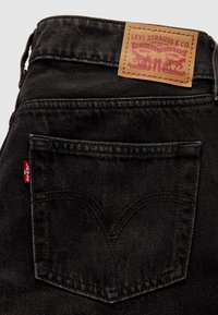 Μαύρα τζιν από τζιν ύφασμα με δερμάτινο ταμπελάκι με λογότυπο, ραφές σε αντίθετο χρώμα και χαρακτηριστικό σχέδιο πίσω τσέπης με διπλή ραφή.