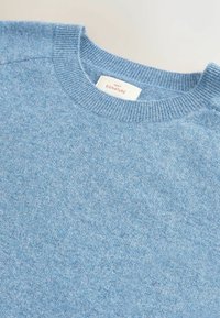 Jasnoniebieski sweter dzianinowy z okrągłym dekoltem i prążkowanym kołnierzem. Miękka tekstura z delikatnym wzorem melanżowym. Metka mówi "Next Signature."