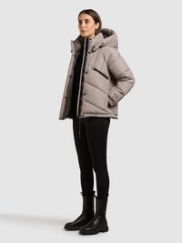 Lysegrå dunjakke med hætte, lynlås foran og sidelommer. Båret over en sort top og kombineret med sorte, klodsete støvler.