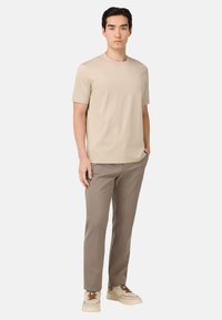 Camiseta de manga corta beige combinada con pantalones ajustados de color marrón claro y zapatillas crema con detalles marrones. Diseño sencillo, textura suave.
